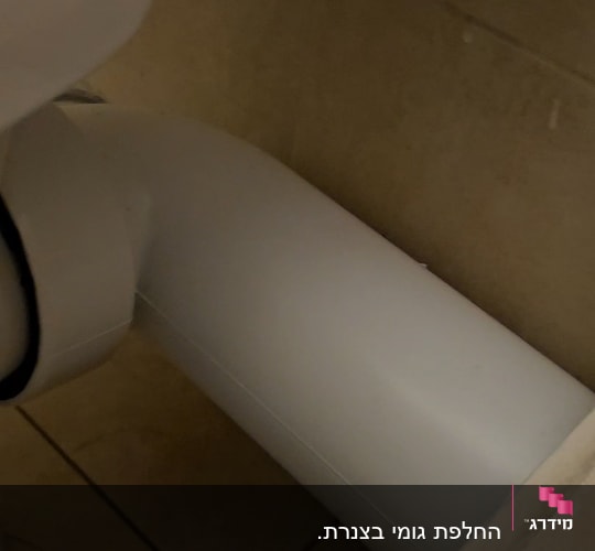 צינור לבן מחובר לאסלה בחדר אמבטיה